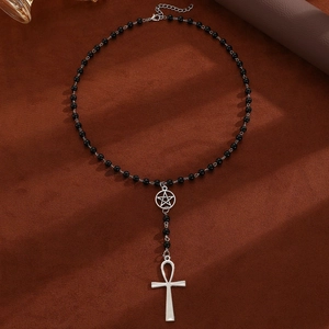 Detail of beaded necklace with silver star and Ankh cross pendant on brown fabric