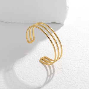 Macro shot of minimalist gold layered cuff bracelet with handcrafted hammered texture