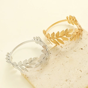 Detailed view of adjustable gold and silver leaf bracelets on a premium stone pedestal