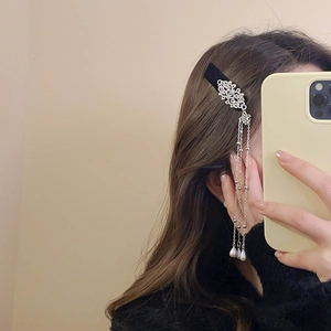 Detail of velvet hair clip with silver floral metal and pearl tassels worn on the side