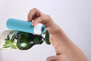 Detail showing the process of pouring liquid into a blue silicone travel bottle for toiletries