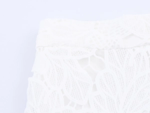 Close-up of white lace fabric with intricate floral patterns on a two-piece skirt set