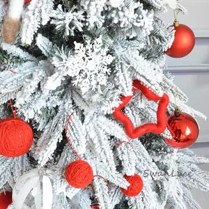 Close-up of red star wool felt and snowflake ornaments on a flocked Christmas tree