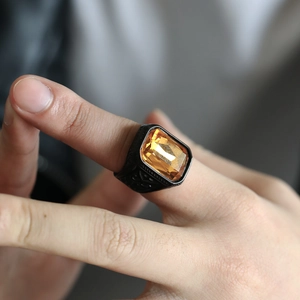 Close-up of vintage black steel ring featuring a yellow square gemstone on a finger