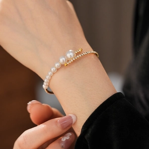 Detail of elegant gold open cuff bracelet with pearls and rhinestones on a woman's wrist