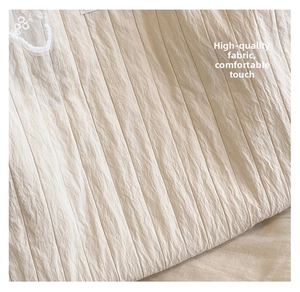 Close-up of crinkled cream fabric texture and delicate white lace detailing on tote bag