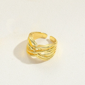 Close-up of golden multi-layer braided open ring with a hollow woven design and wide texture
