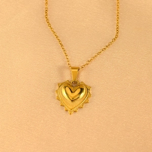 Macro shot of gold heart pendant with radial texture on elegant champagne background
