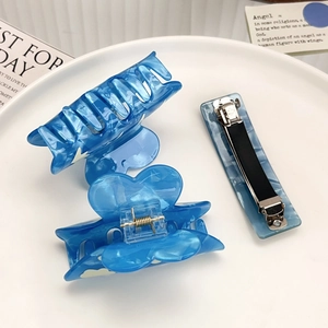 Three-piece set of blue acetate hair clips with marble texture on a white decorative plate