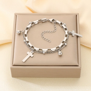 Detail of silver double-layer cross bracelet with beads and adjustable chain on satin