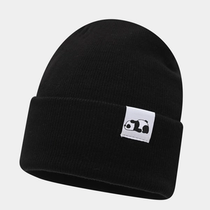 Close-up of black knitted beanie with a cute panda patch showing fine textile texture