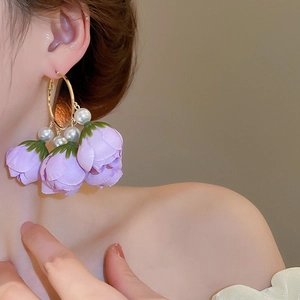 Detailed view of floral tassel earrings with purple fabric petals and white pearls