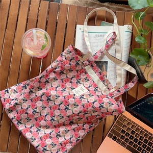 Detail of a floral canvas tote bag featuring vintage pink rose patterns and wide straps