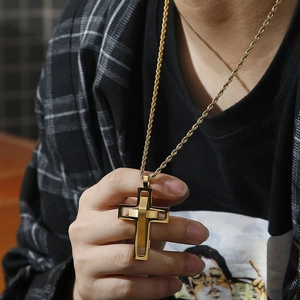 Close-up of golden layered cross pendant with twist chain worn by a male model