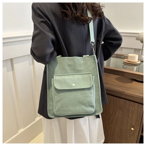 Detail of light green corduroy tote bag with large front flap pocket shown on model