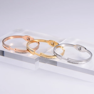 Detailed shot of Roman numeral bangles in rose gold, gold, and silver with zircon accents