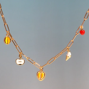 Detail of gold chain necklace featuring enamel fruit charms including orange and strawberry