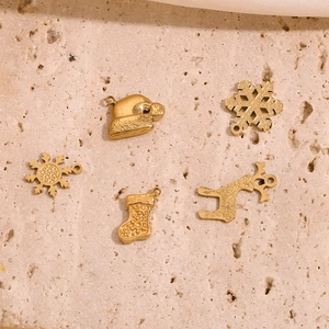 Dettaglio di ciondoli natalizi dorati con renne e fiocchi di neve su sfondo di pietra