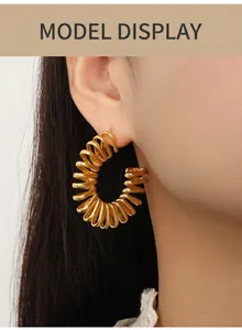 Gros plan de boucles d'oreilles spirales dorées en C portées par un mannequin chic