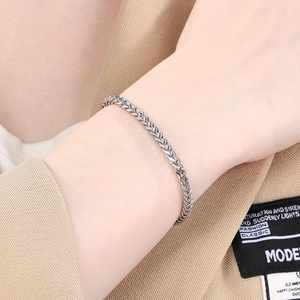 Close-up of men's stainless steel wheat chain bracelet worn with a khaki suit sleeve