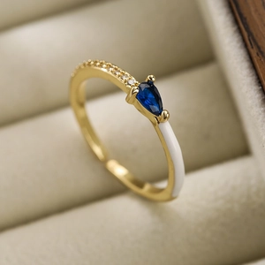 Detailed macro of a gold-plated pear-cut zircon ring with white enamel in a jewelry box