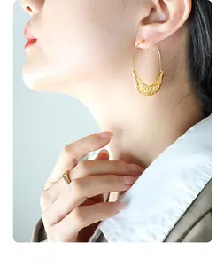 Detail of vintage gold hoop earrings with hammered texture and a rhinestone ring