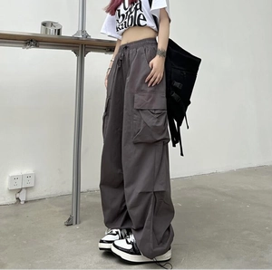 Detail view of dark grey cargo pants with side pockets and a loose parachute fit