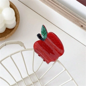 Sparkly red apple hair claw clip in acrylic with green leaf on a white grid background