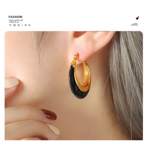 Detailed close-up of C-shaped black enamel and gold earrings on a model's ear