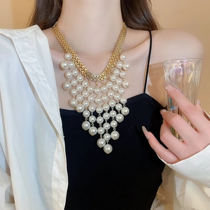 Détail d'un collier de perles multicouches avec chaînes dorées porté par un mannequin