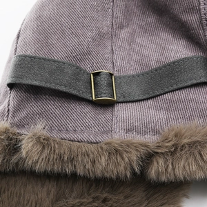 Close-up of winter trapper hat with metal buckle, faux fur trim and corduroy fabric
