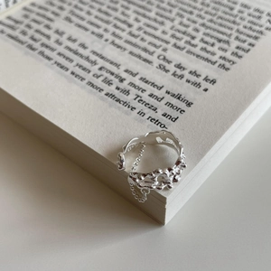 Detail view of S925 sterling silver irregular lava ring with delicate chain on a book