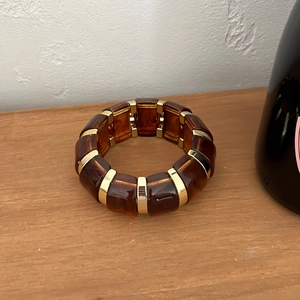 Gros plan du bracelet en résine ambre avec intercalaires dorés sur surface en bois