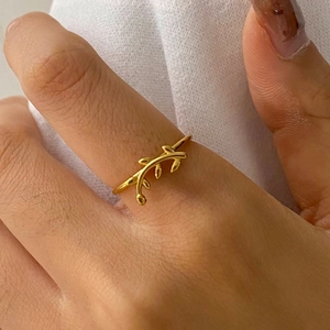 Close-up of golden stainless steel branch ring with leaves on a finger