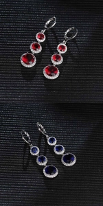 Close-up of teardrop zircon earrings set with red and blue crystals and small diamonds