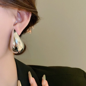 Close-up of a silver water drop earring featuring a polished mirror finish on a model