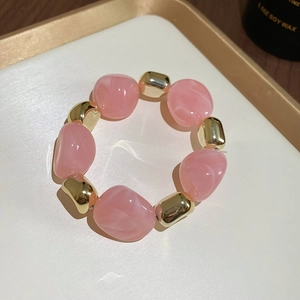 Close-up of pink irregular acrylic beads and gold metallic spacers on a display tray