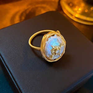 Dettaglio macro di anello con perla barocca avvolto in filo d'oro e zircone