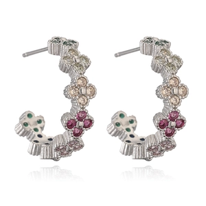 Macro shot of silver clover earrings with colorful zircon stones on a white background