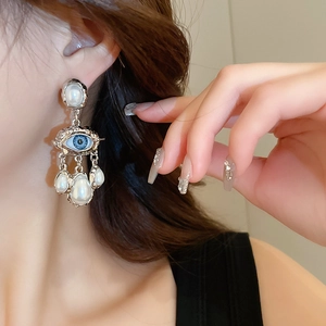 Close-up of vintage eye earrings with blue resin and dangling teardrop faux pearls