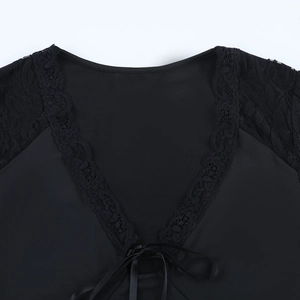 Detail of V-neck lace patchwork top featuring a delicate bow tie and black smooth fabric