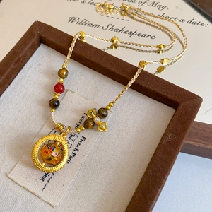 Close-up of vintage gold pearl necklace with rotating enamel ball and woven rope detail