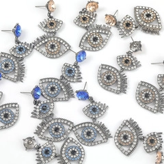 Macro detail of alloy evil eye earrings with blue crystals and sparkling white rhinestones