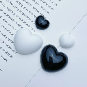 Detail of black and white heart resin charms in glossy and matte finishes for DIY crafts
