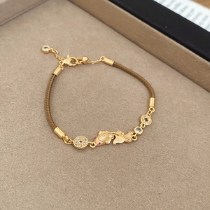 Detailed macro view of a gold koi carp and copper coin bracelet with brown cord