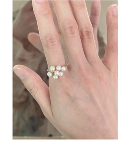 Close-up of a gold ring featuring a cluster of white pearls worn on a finger
