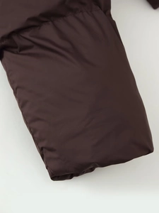 Detailed close-up of dark brown puffer jacket cuff showing smooth nylon fabric and stitching