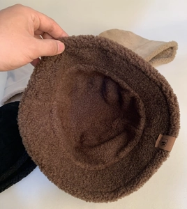 Close-up of thick coffee brown faux shearling texture and leather logo on bucket hat
