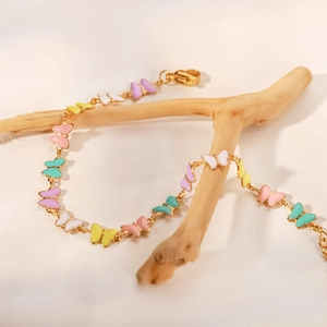 Nahaufnahme des goldenen Schmetterling-Armbands aus Edelstahl mit bunter Emaille