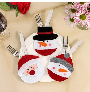 Three festive Santa and snowman cutlery holders set on a plate for Christmas dining decoration